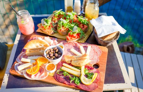 Tasty italian snack. Fresh bruschettes, cheeses and meat on the board in outdoor cafe with amazing view in Manarola